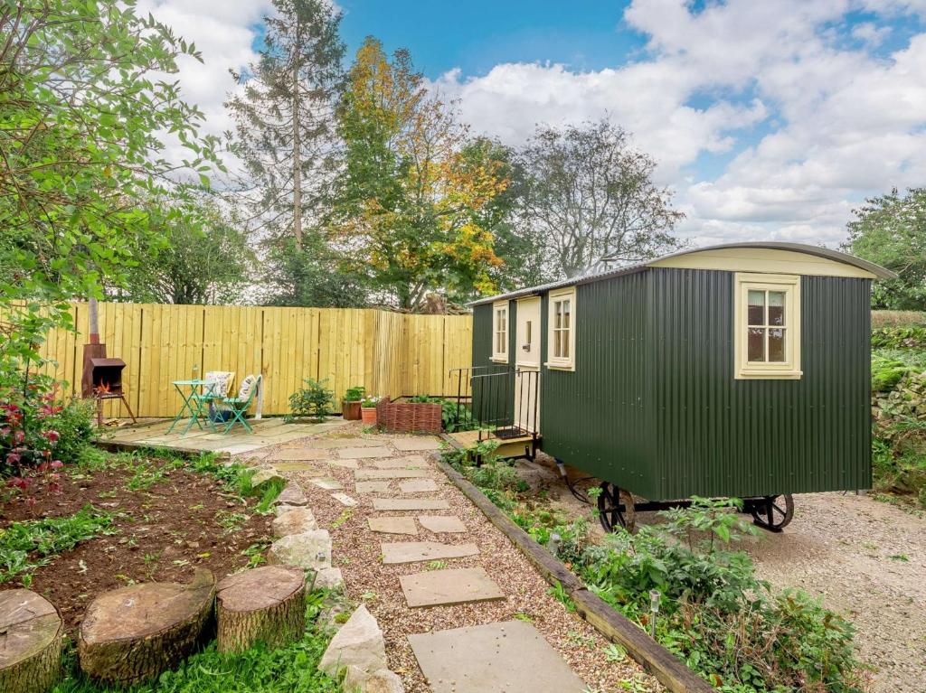 a green tiny house in a backyard with a fence at 1 Bed in Alsop-en-le-Dale 90021 in Alsop en le Dale