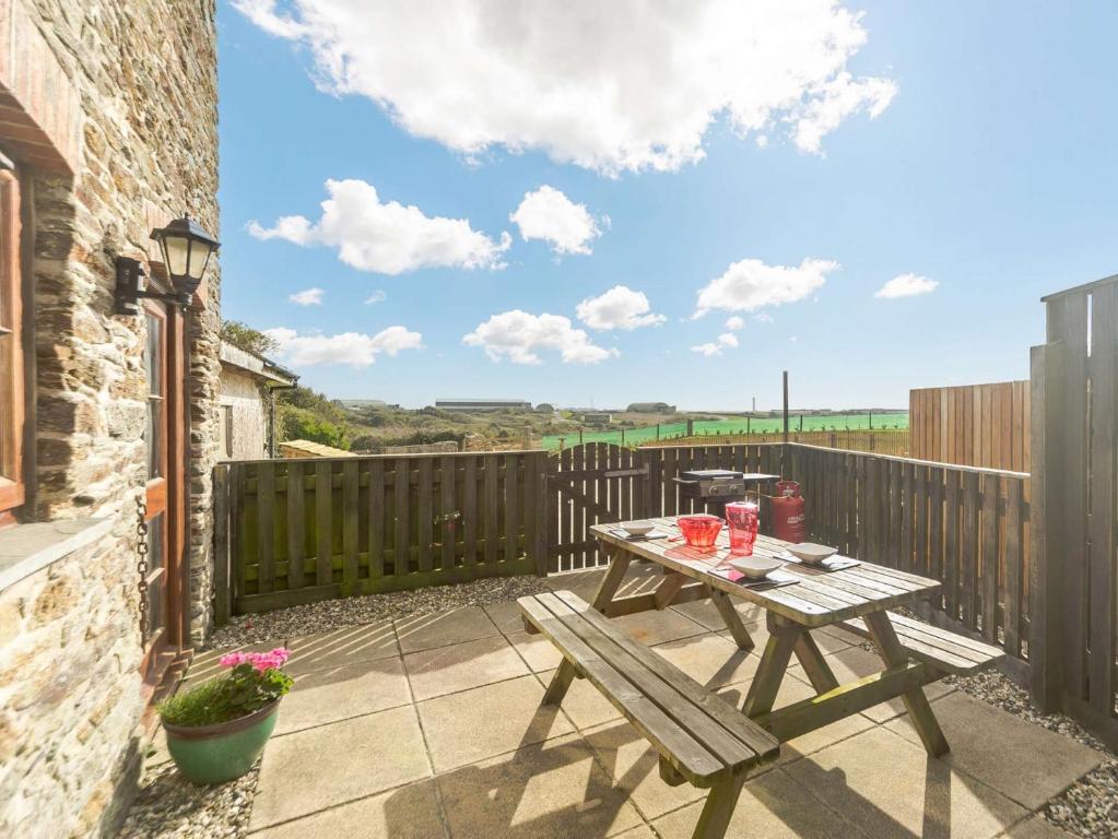 a patio with a wooden table and a wooden fence at 1 Bed in Newquay 89942 in Mawgan Porth