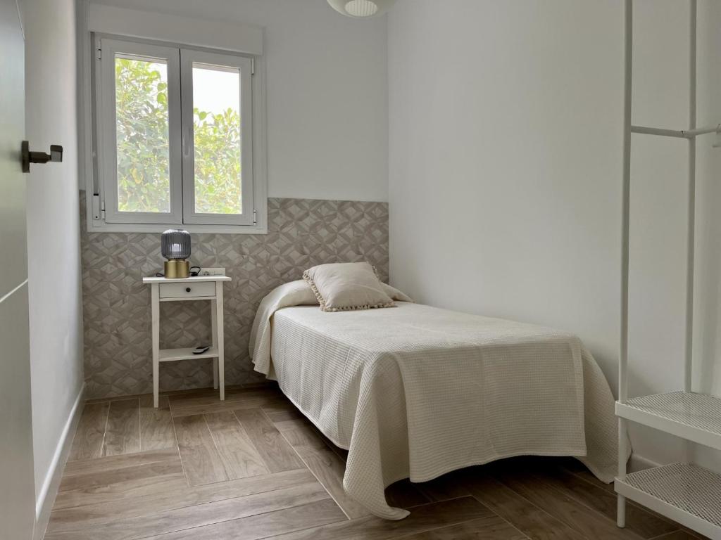 a white bedroom with a bed and a window at HELICES CENTRO SAN JOSE CABO DE GATA in San José