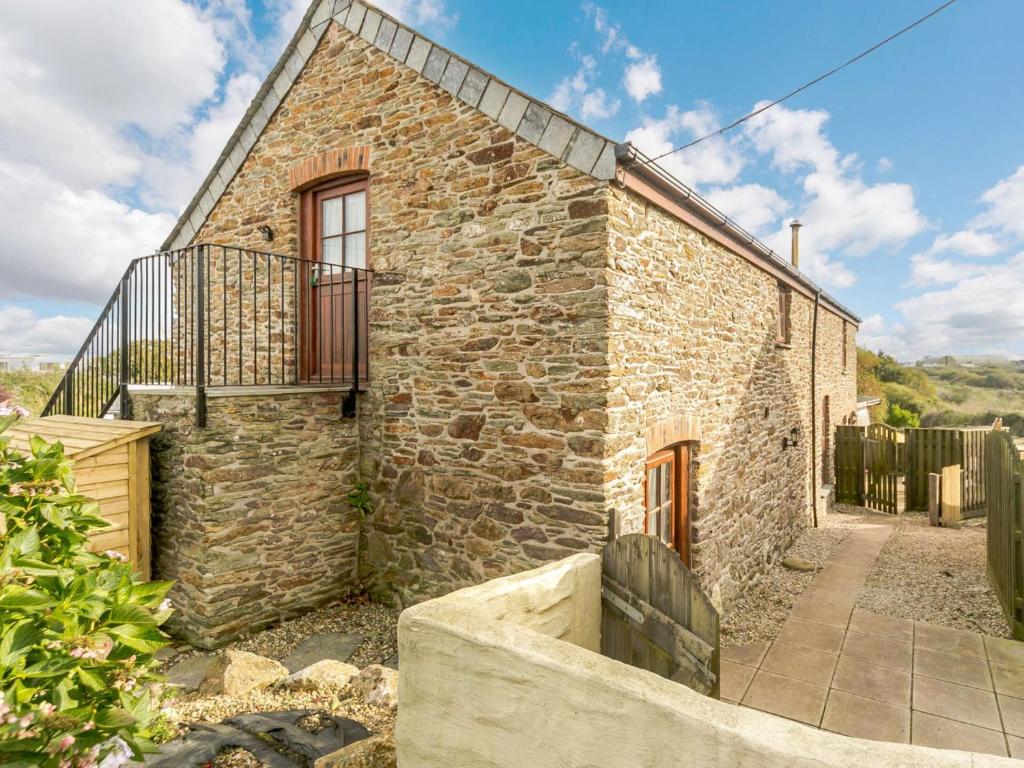 una casa de piedra con un balcón en un lateral. en 3 Bed in Newquay 89941, en Mawgan Porth