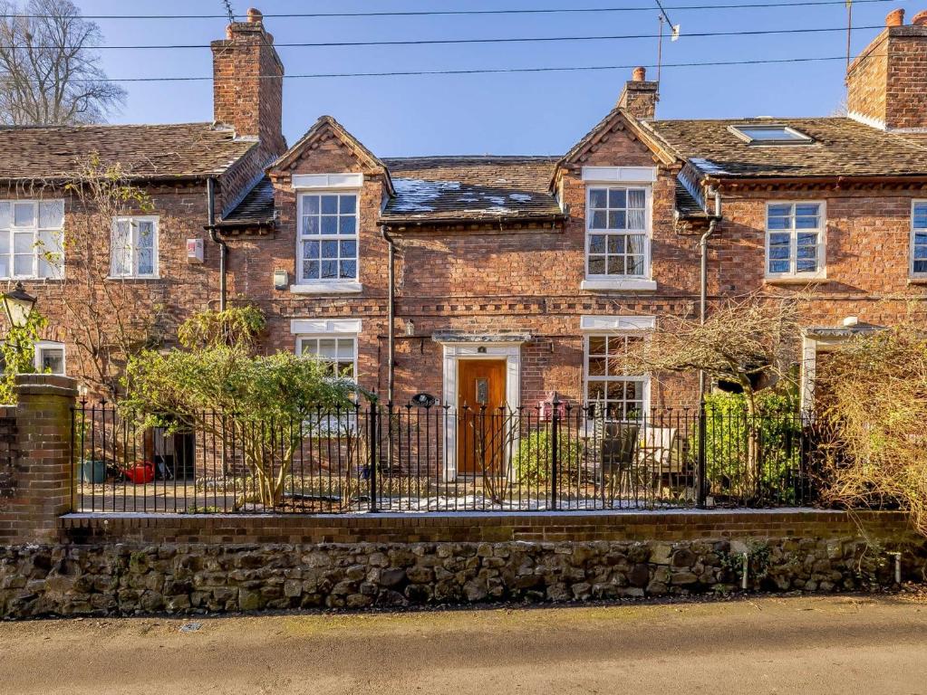 una antigua casa de ladrillo con una valla de hierro forjado en 2 Bed in Ironbridge 89961 en Coalbrookdale