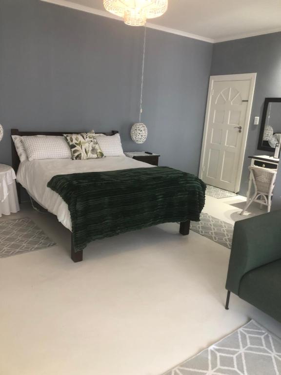 a bedroom with a bed with a green blanket at Kellys Corner in Lydenburg