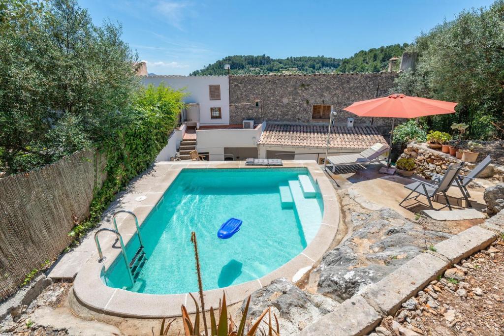einen Pool im Garten mit Sonnenschirm in der Unterkunft Can Bessó Mancor de la Vall in Mancor del Valle