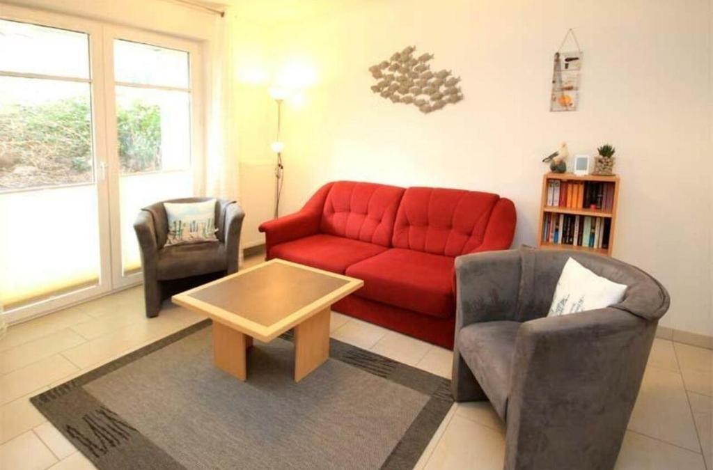 a living room with a red couch and two chairs at Strandschloesschen-Haus-II-WE-4-9699 in Kühlungsborn