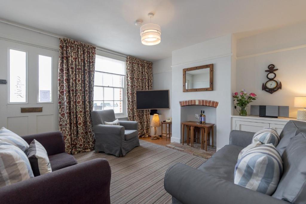 ein Wohnzimmer mit einem Sofa, einem TV und einem Stuhl in der Unterkunft Spyglass, Southwold - Stunning sea views in Southwold