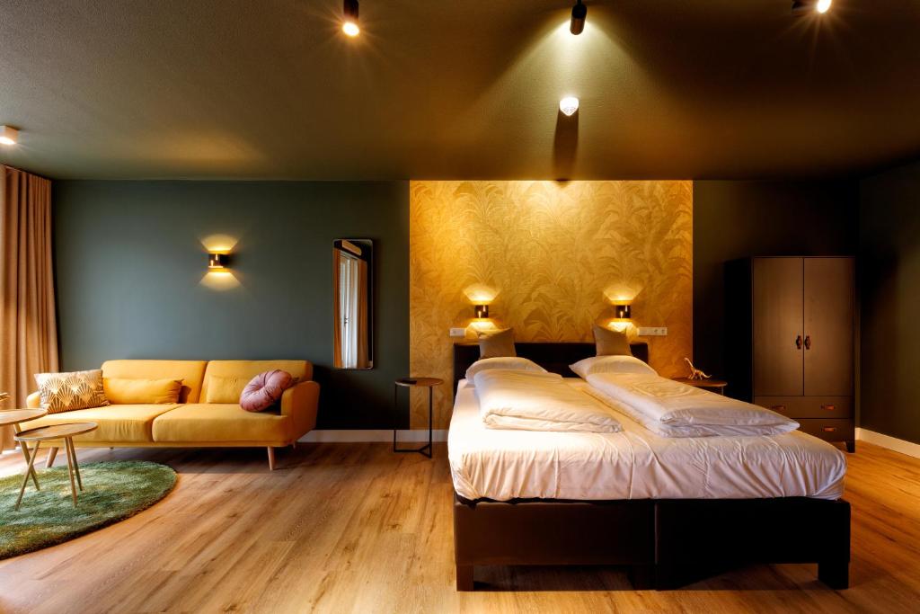 een slaapkamer met een bed en een bank bij Wapen van Hengelo Residence Suites - digital key by SMS and email in Hengelo