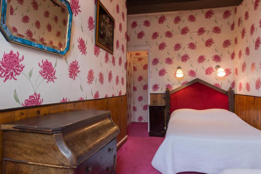 a bedroom with a red bed and pink walls at Hotel Esmeralda in Paris
