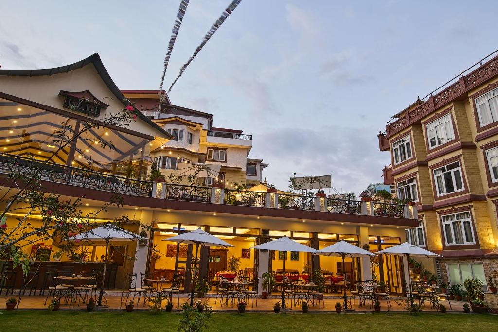 a building with tables and umbrellas in front of it at Shambaling Boutique Hotel in Kathmandu