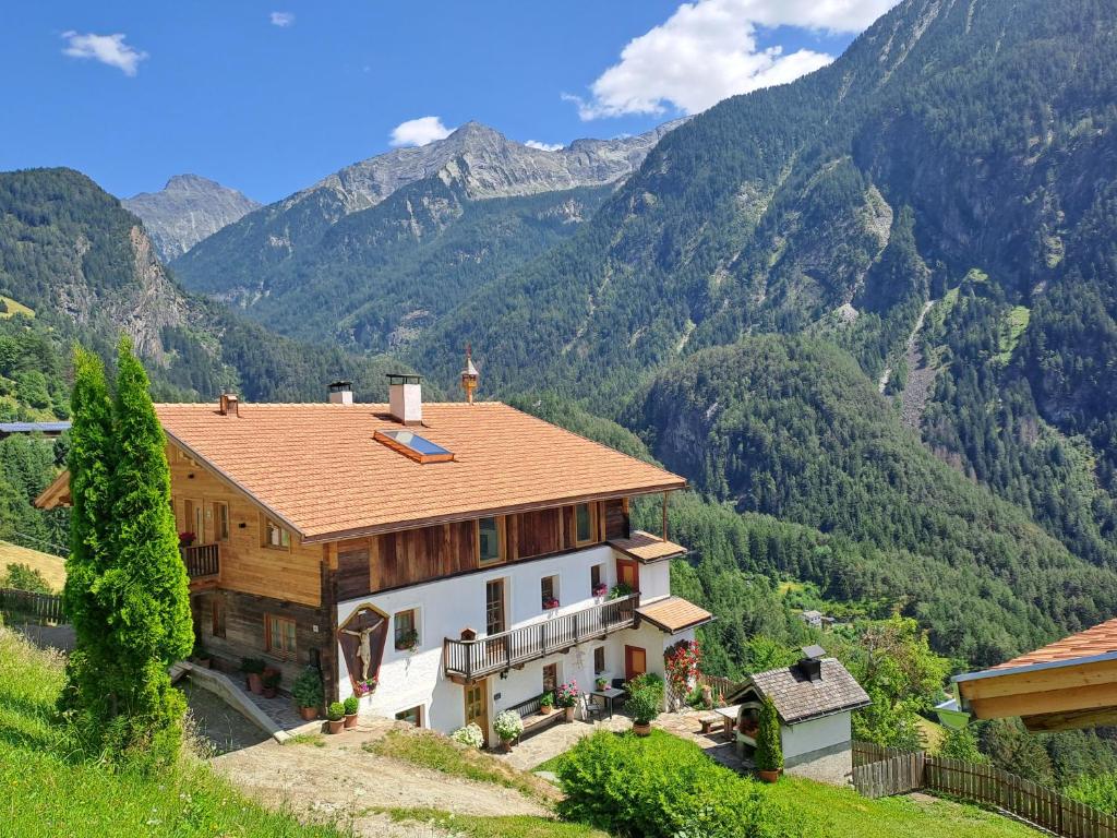 a house on a hill with mountains in the background at Appartstube Wasserfallspitz in Sand in Taufers