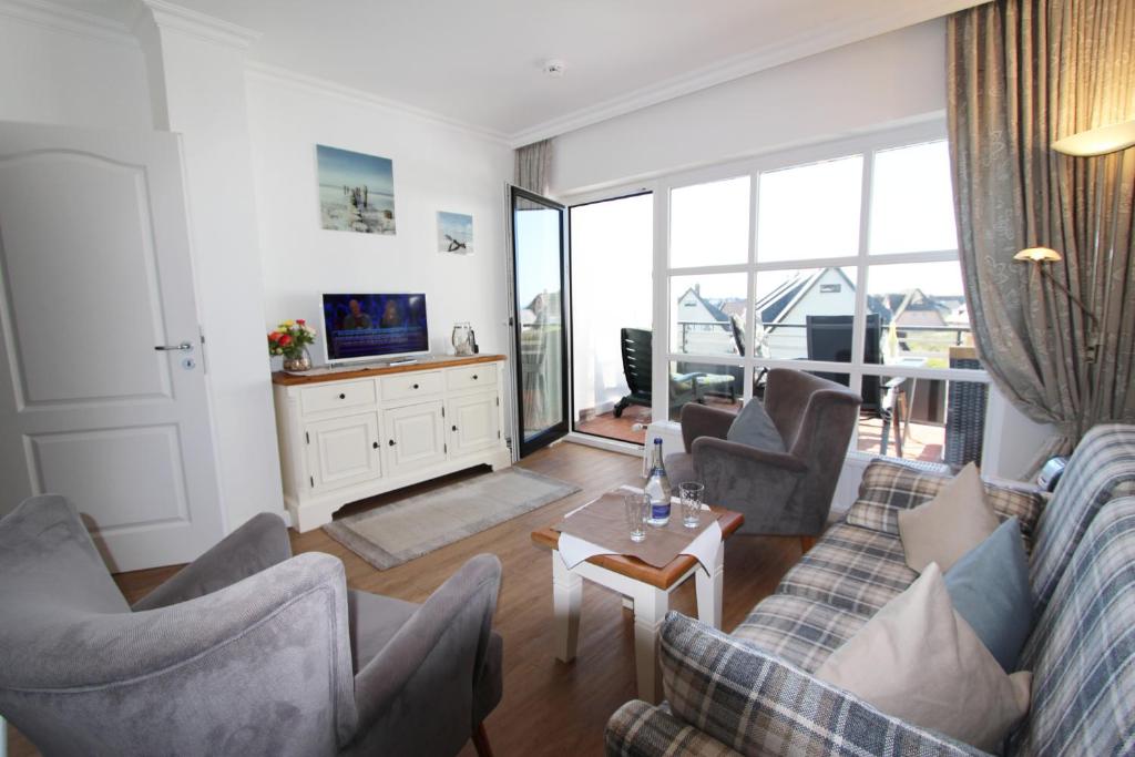 un salon avec un canapé, des chaises et une télévision dans l'établissement Atlantik - Strandstr 15, App 12, à Wenningstedt