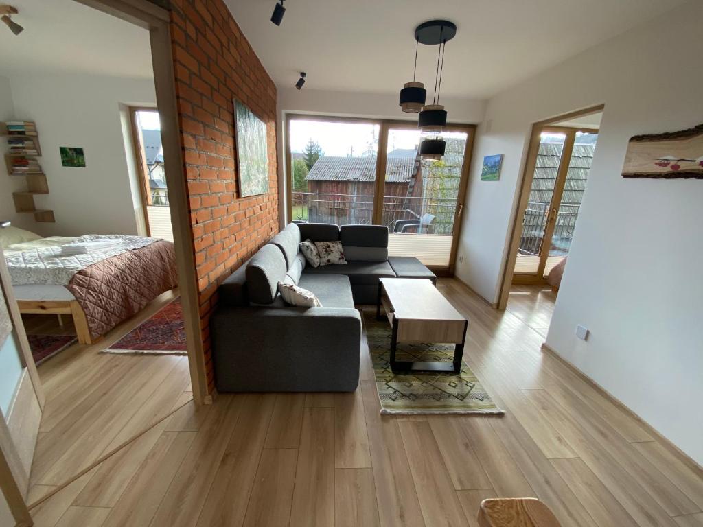 a living room with a couch and a brick wall at Apartamenty Cicha Dolina in Jurgów