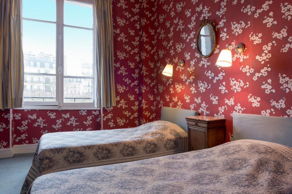 a bedroom with two beds and a window and red walls at Hotel Esmeralda in Paris