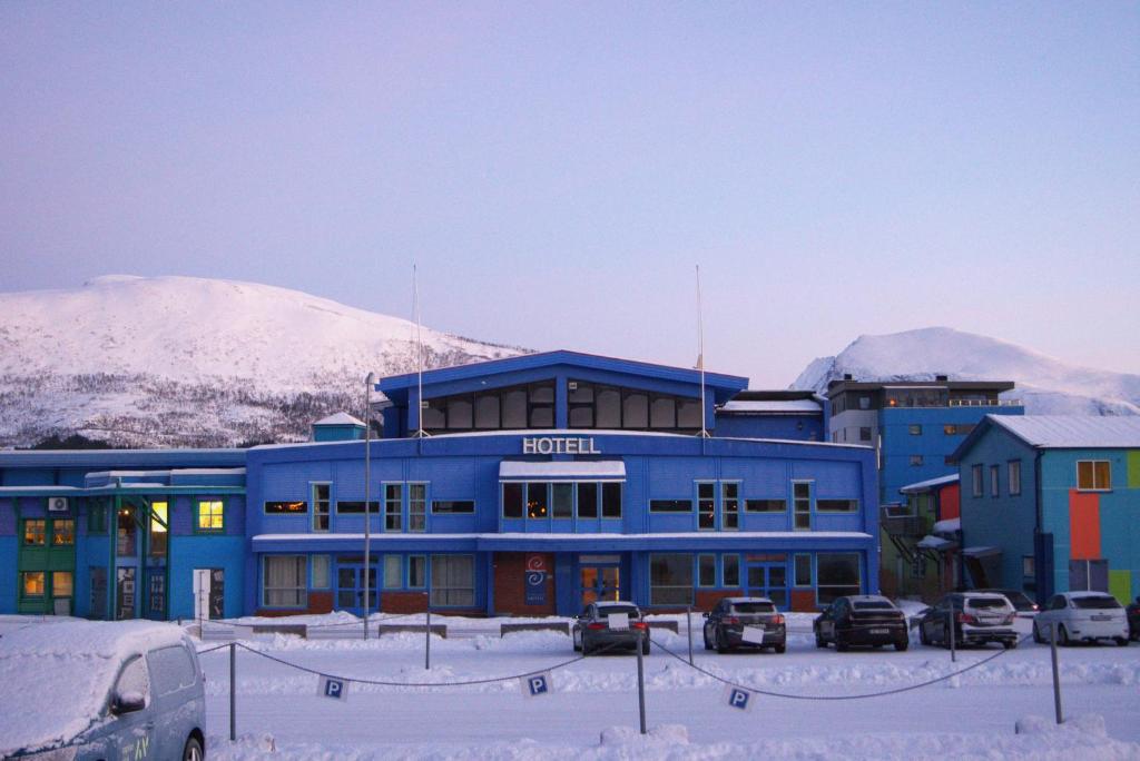 un edificio azul con coches estacionados en un estacionamiento en True Vesterålen Hotel, en Sortland