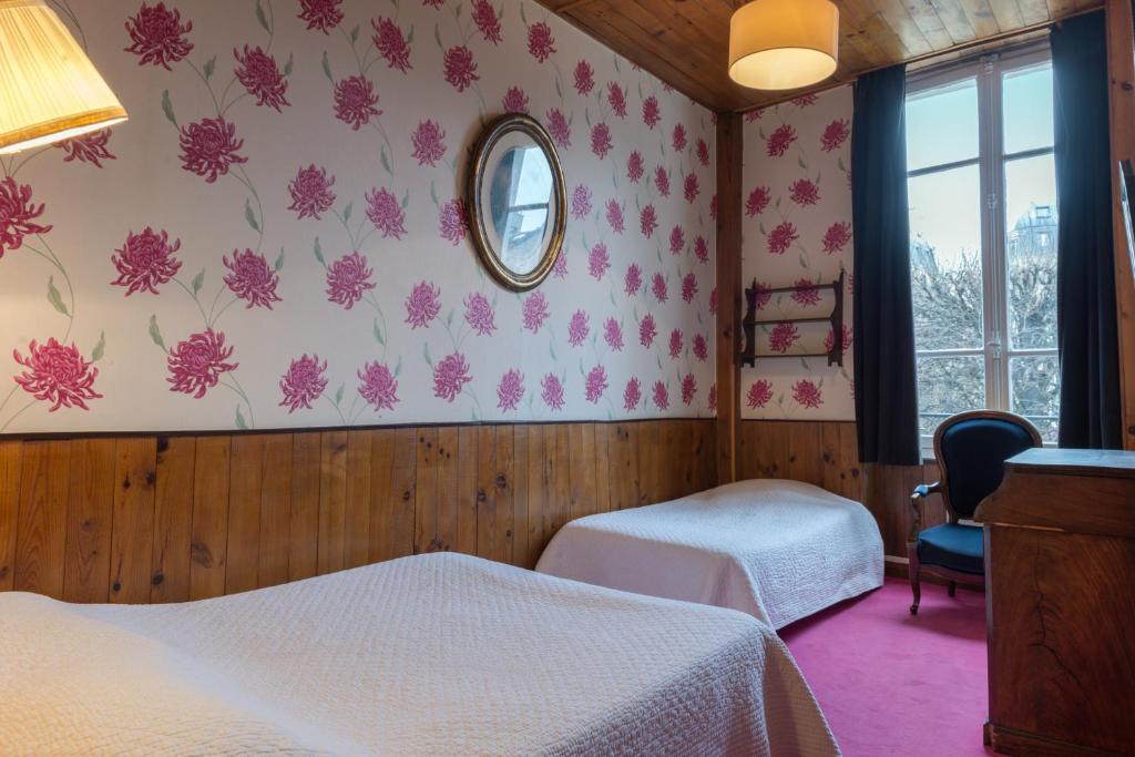 a hotel room with two beds and a mirror at Hotel Esmeralda in Paris