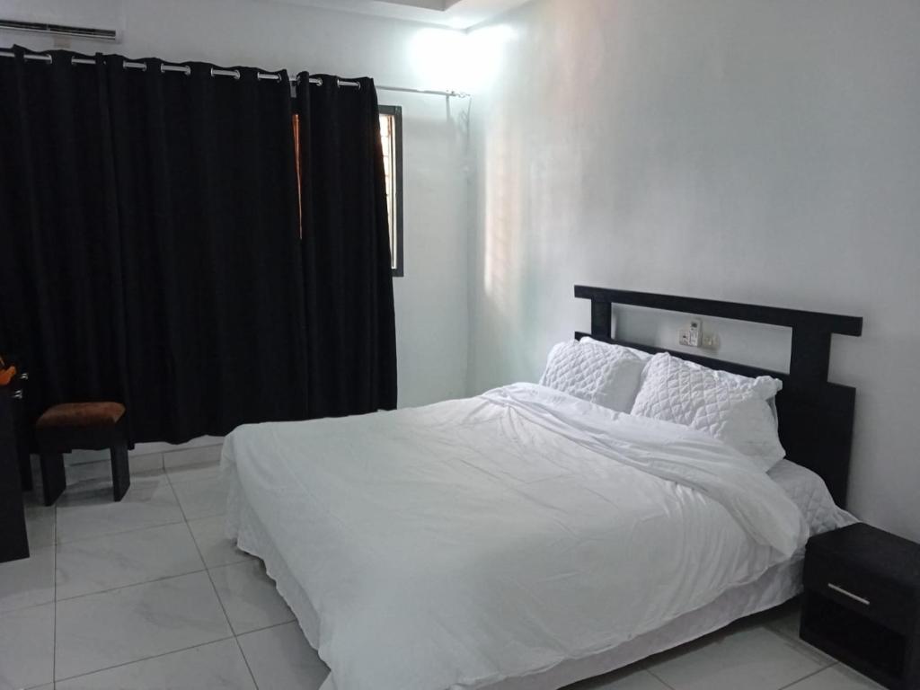 ein Schlafzimmer mit einem weißen Bett und einem schwarzen Vorhang in der Unterkunft Luxury 2- Apartment Furnished luxury residence in Cocody