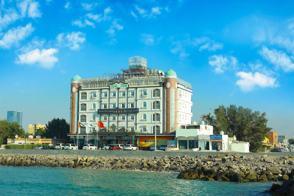 um grande edifício branco sentado ao lado de uma massa de água em Great Wall Hotel em Ras al-Khaimah