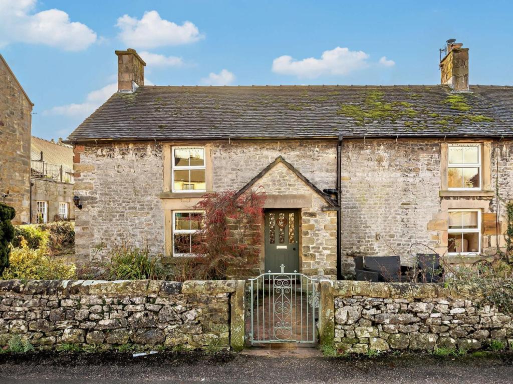 ein altes Steinhaus mit einem Tor und einer Steinmauer in der Unterkunft 3 Bed in Hartington 90125 in Hartington