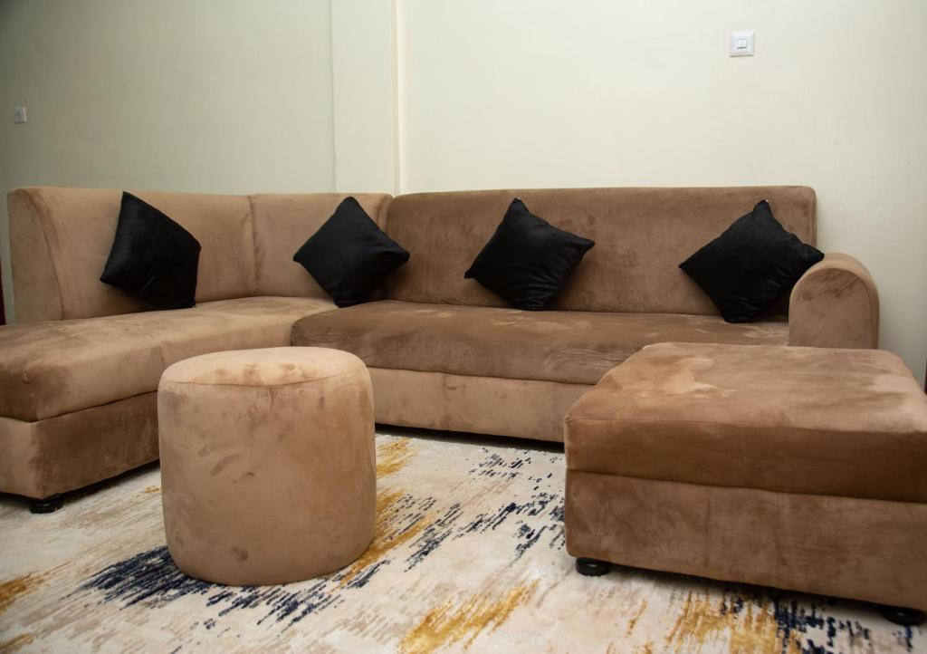 ein Wohnzimmer mit einem braunen Sofa und zwei Ottomanen in der Unterkunft FG Homestay, Kampala Muyenga-Bukasa in Kampala