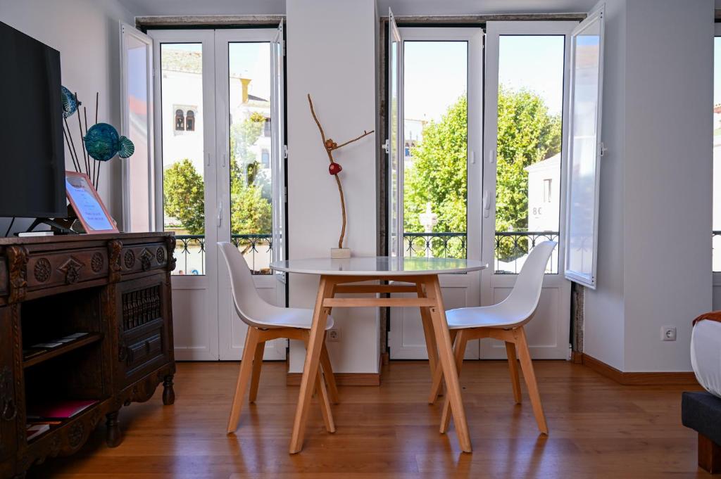 una mesa y sillas en una habitación con ventanas en Casa do Briamante 6 en Sintra