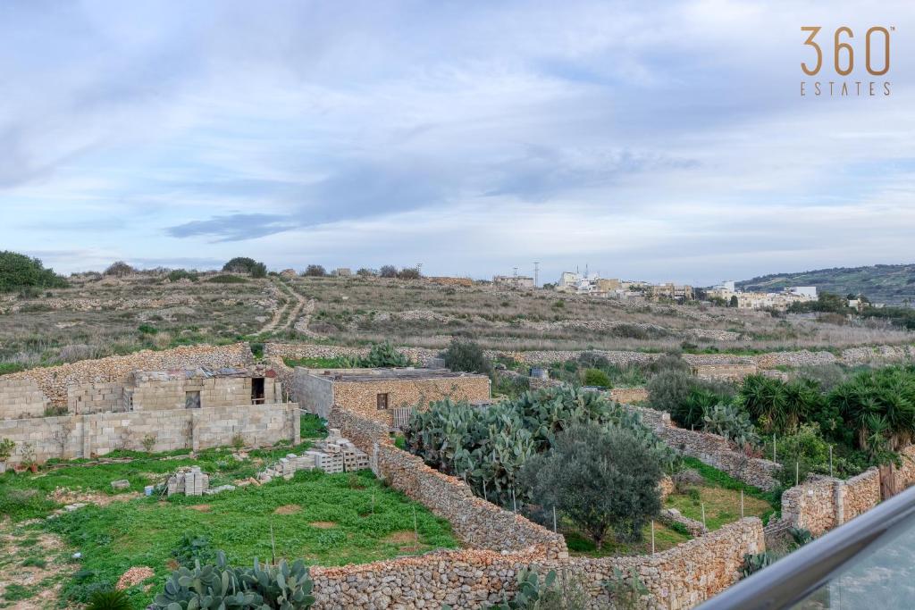 un antiguo edificio de piedra en una colina con árboles en Lovely 3BR Apt with Private Balcony & Views in Mgarr by 360 Estates en Mġarr
