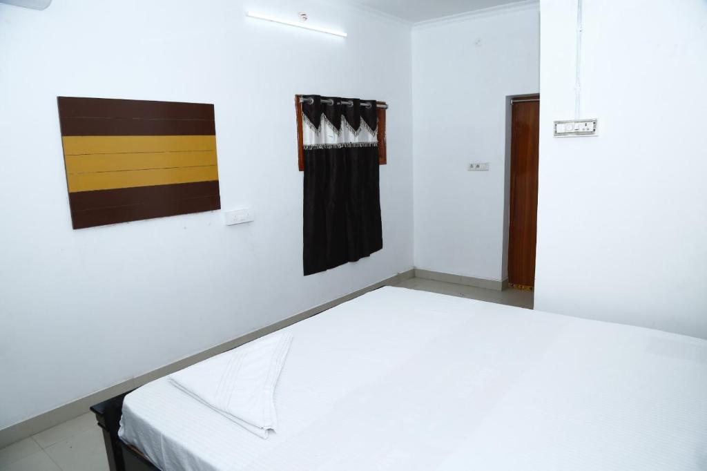 een kamer met een bed en twee schilderijen aan de muur bij Sri Naari inn in Kondavīdu