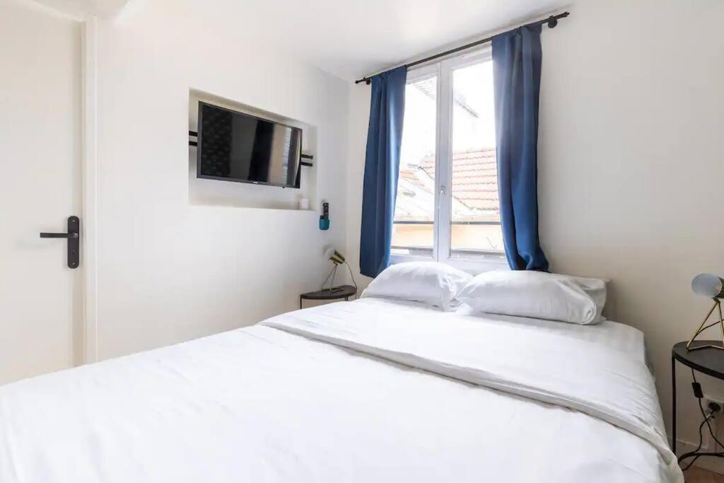 une chambre avec un grand lit blanc avec une fenêtre dans l'établissement Grands Boulevards 52 Appartement Cosy 1BR-4P, à Paris
