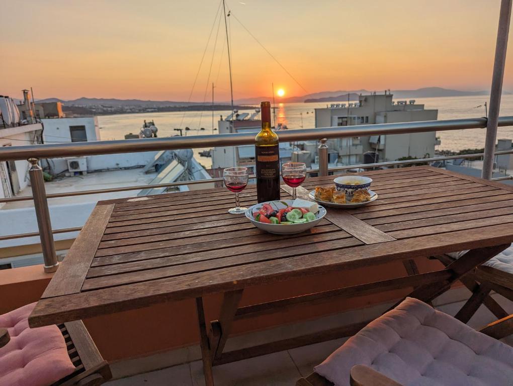 un tavolo in legno con una bottiglia di vino e una ciotola di cibo di Tamar's place a Chania