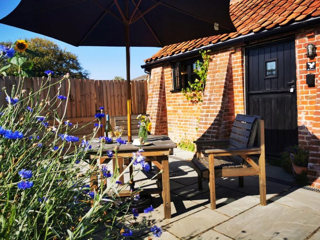 a patio with a table and a chair and an umbrella at 1 Bed in Burgh St Peter 90192 in Burgh Saint Peter