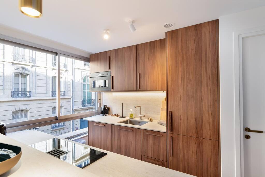 a kitchen with wooden cabinets and a sink at La Perle de Kléber in Paris