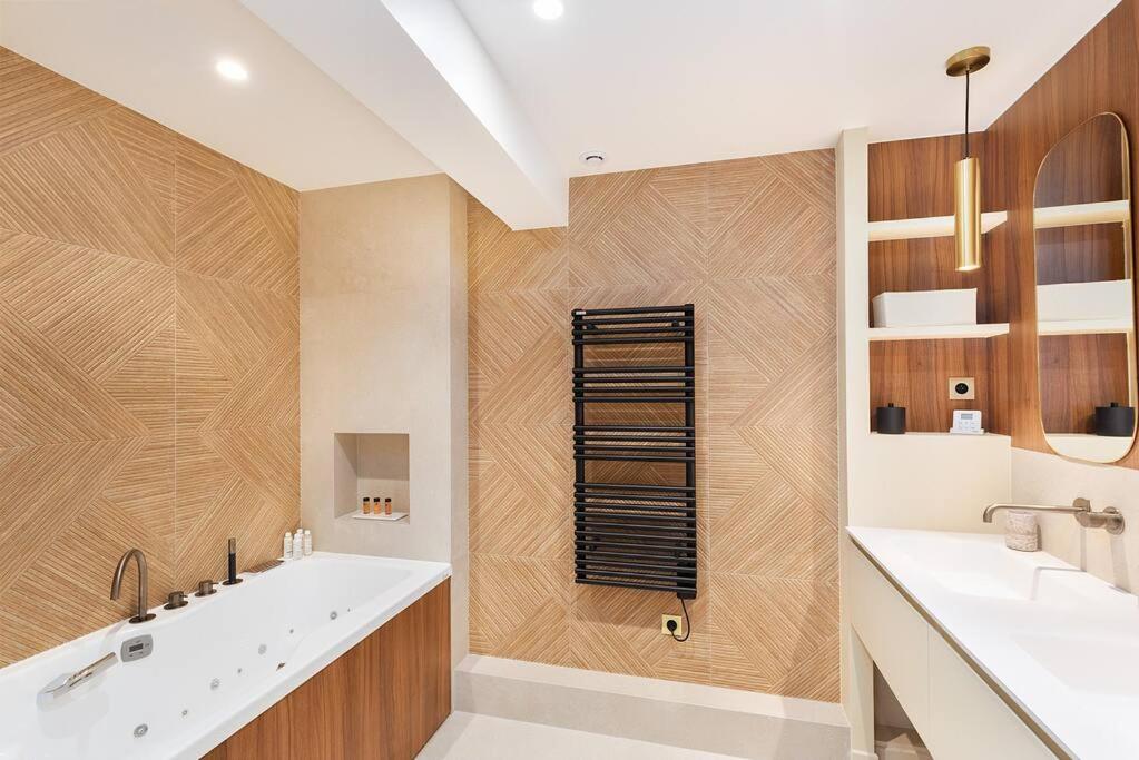 a bathroom with a large white tub and wooden walls at La Perle de Kléber in Paris