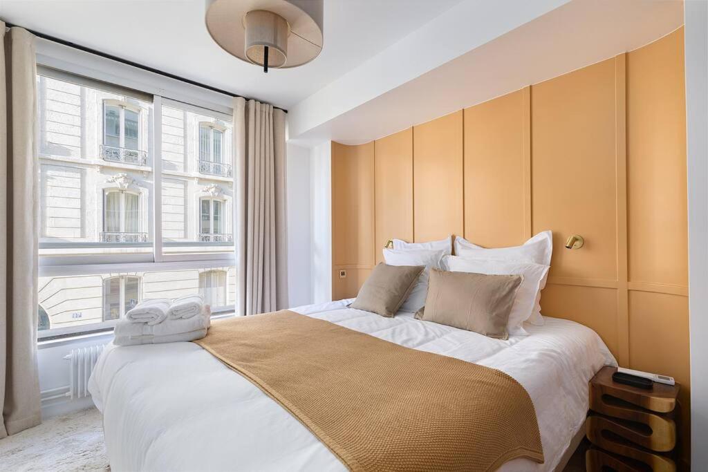 a bedroom with a large bed with a large window at La Perle de Kléber in Paris