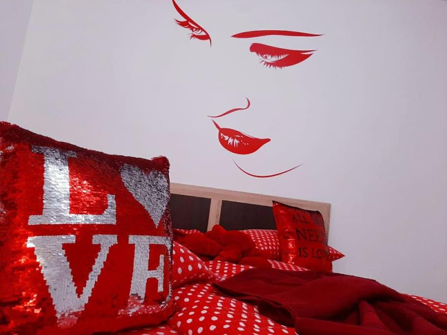 a bedroom with a bed with red sheets and red lips at Cazare Centru Brasov in Braşov