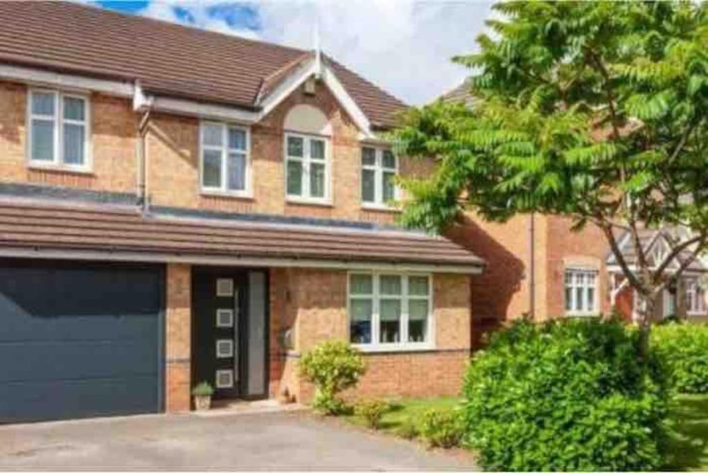 a brick house with a garage and a tree at Spacious 3-bed Home - Nature Reserve Retreat in Ince-in-Makerfield