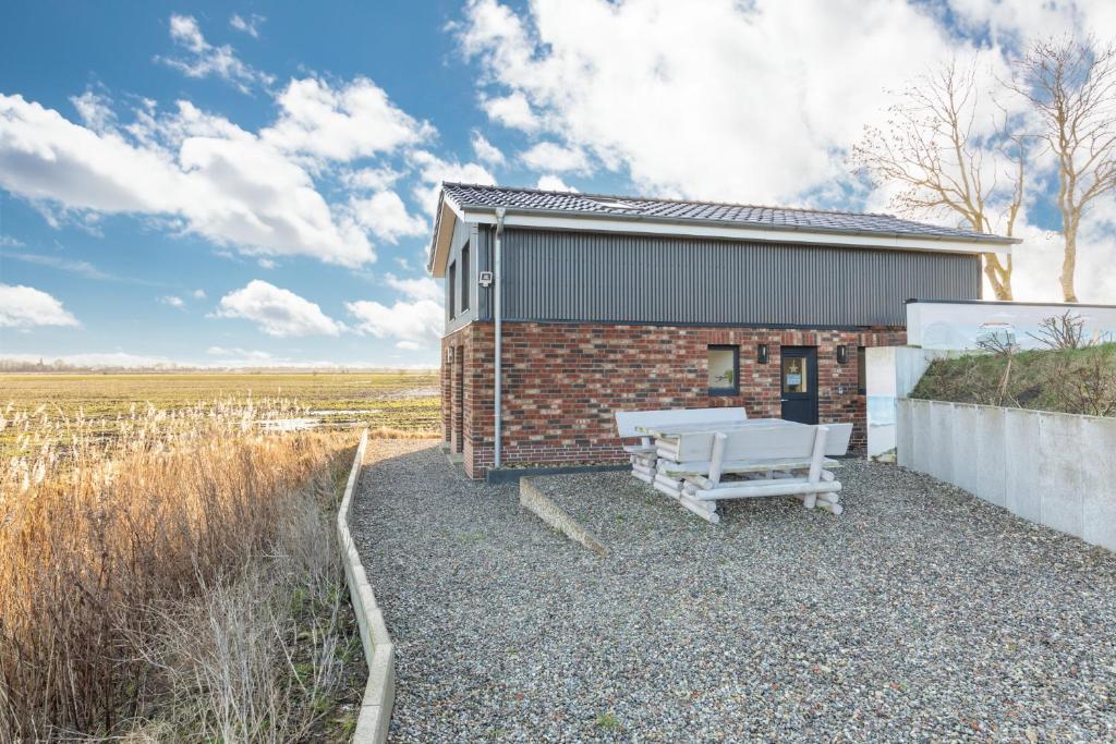 een bakstenen gebouw met een bank ervoor bij Tinyhouse Fofteinbutze in Nordstrand