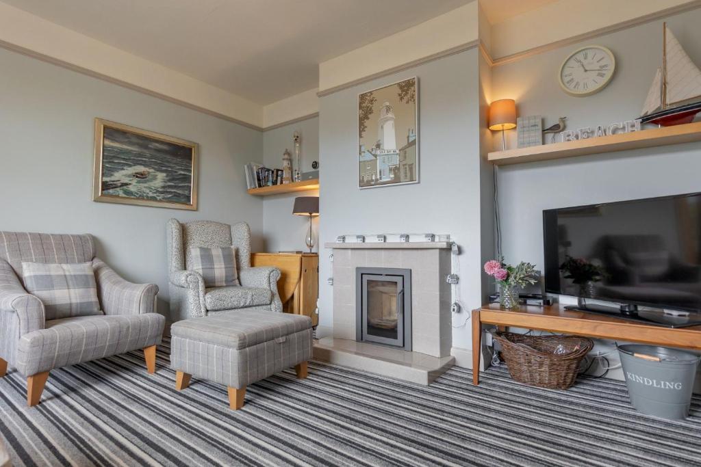a living room with a fireplace and a tv at Sea Mist in Southwold