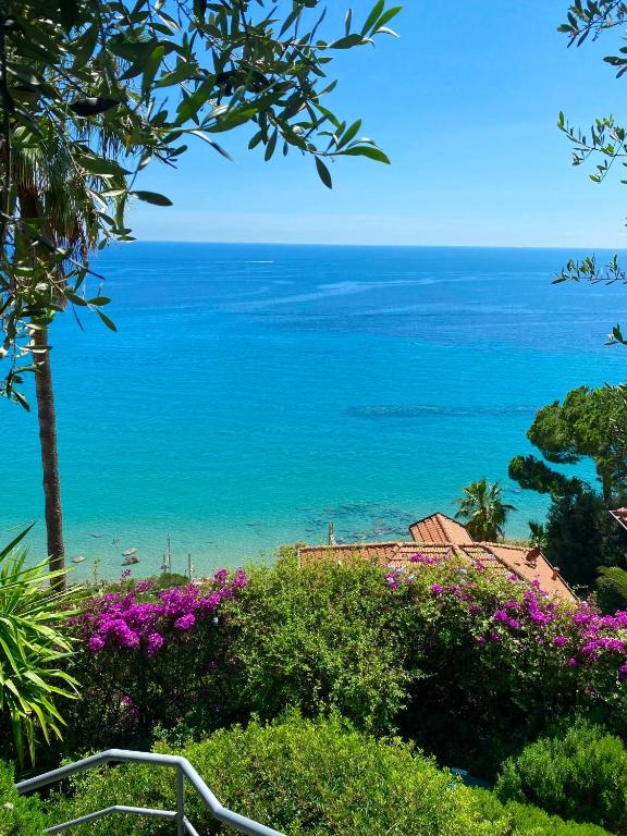a view of the ocean from a hill with flowers at Botanic Garden Apartment Calandre Beach Ventimiglia in Ventimiglia