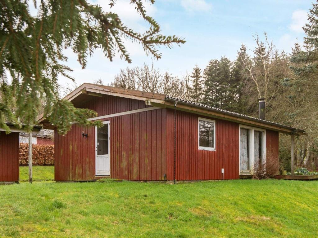 ein rotes Haus mit grünem Rasen davor in der Unterkunft 6 person holiday home in F rvang in Fårvang