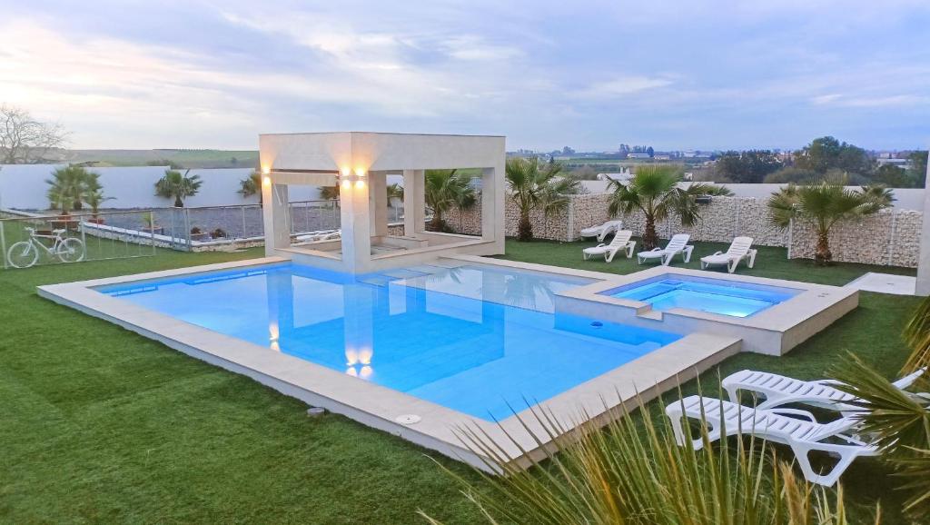a swimming pool on a lawn with chairs around it at Casa FERTONIA in Fuentes de Andalucía