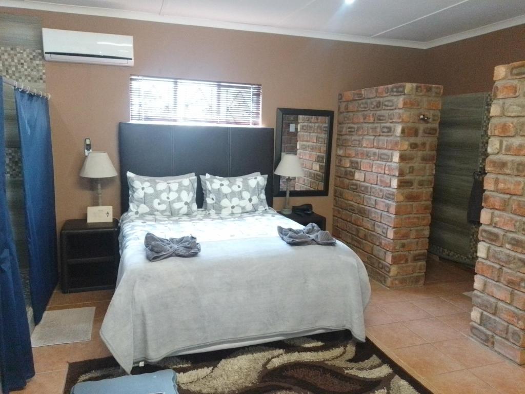 a bedroom with a large bed and a brick wall at Aub Guesthouse - Mariental in Mariental