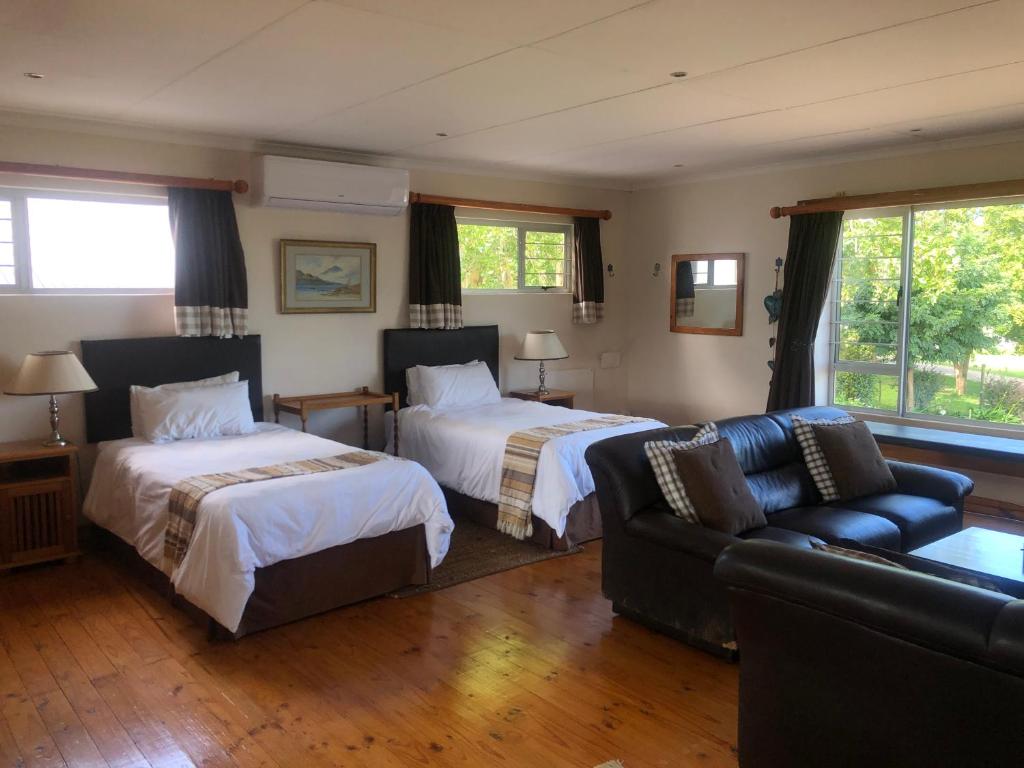 een woonkamer met 2 bedden en een bank bij Bee’s Knees Cottage in Winterton