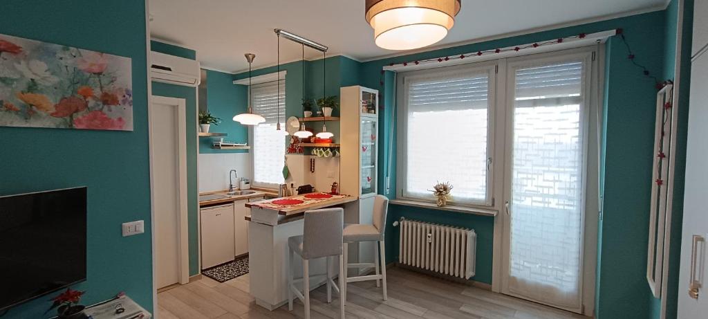 a kitchen with green walls and a table and chairs at L'alloggetto sul Corso in Cuneo