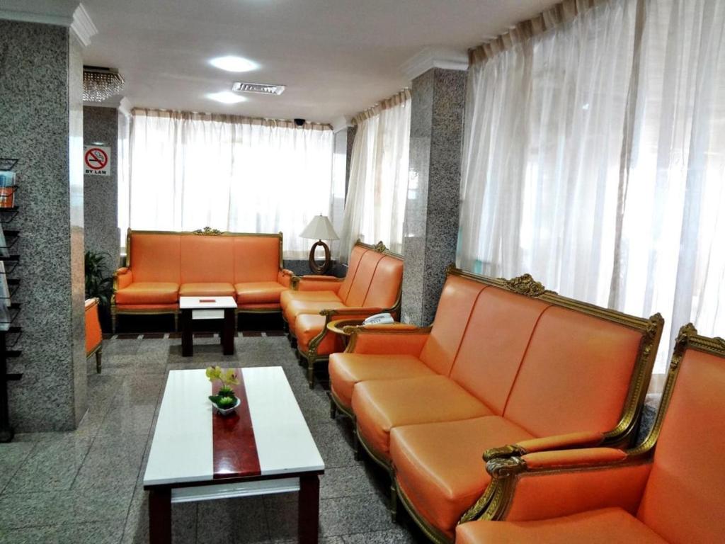 a waiting room with orange couches and a table at Partition Rooms in Hotel Apartment in Dubai