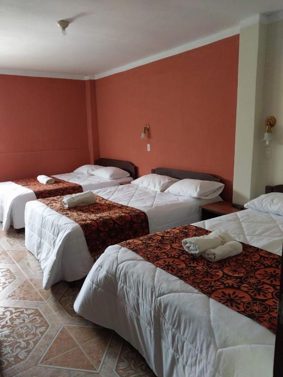 three beds in a room with red walls at Monte Gocta in Valera