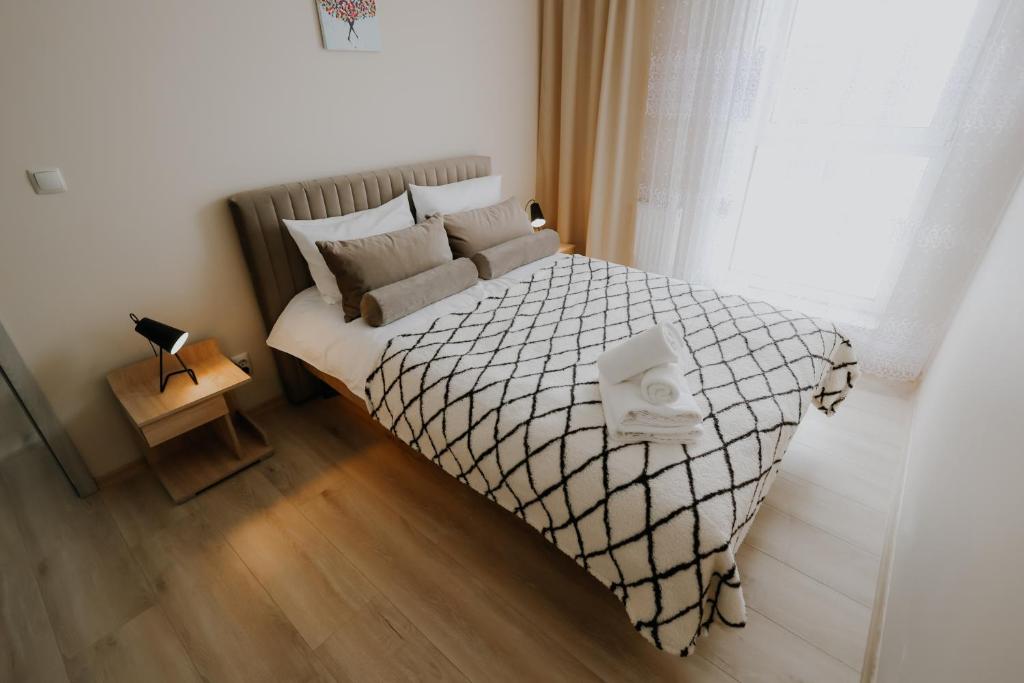 um quarto com uma cama grande com lençóis brancos e uma janela em Nowy Złocień Comfort Apartment em Cracóvia