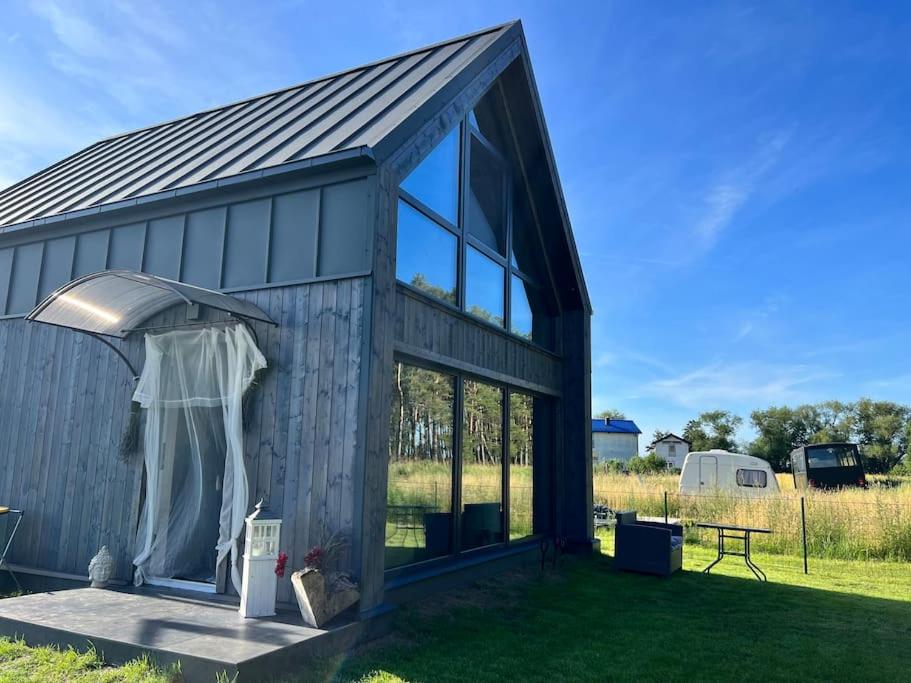 a gray barn with a door and windows at Ferienhaus“ Blaues Wunder“ am Wasser mit Grill in Nowe Warpno