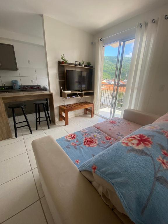 a bedroom with a bed and a desk and a television at Quarto em Florianópolis in Florianópolis