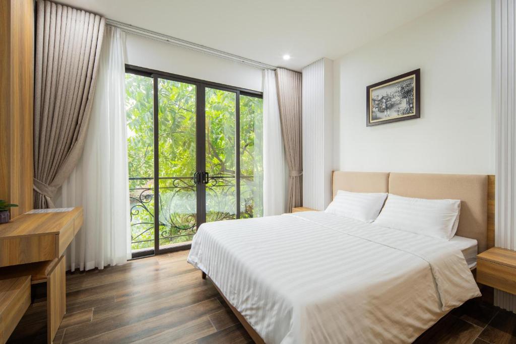 1 dormitorio con cama blanca y ventana grande en Studio-Vincent Apartment HaNoi, en Hanói