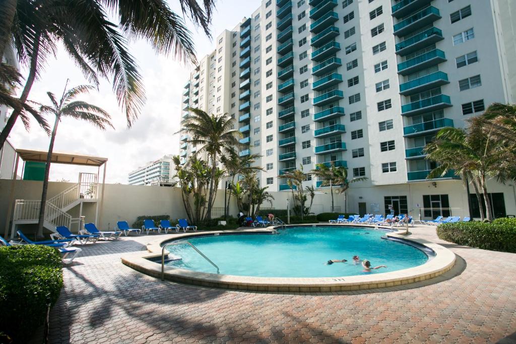a swimming pool in front of a building with palm trees at Sian Oceanfront Condos in Hollywood
