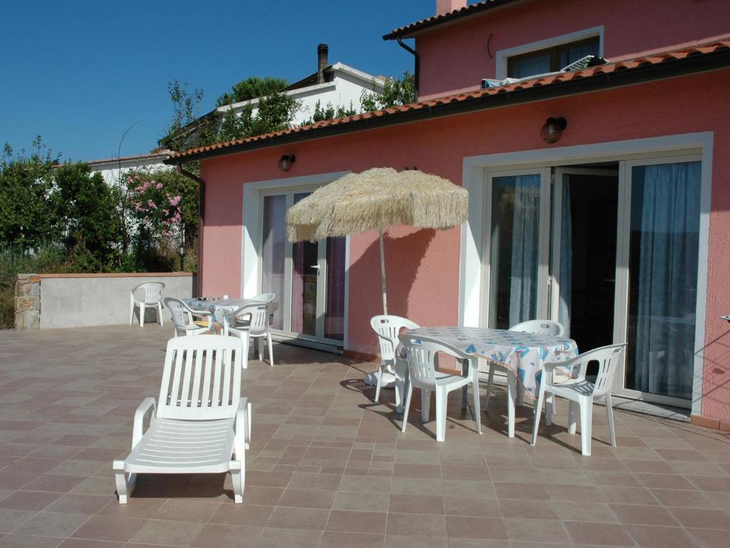 een patio met een tafel en stoelen en een parasol bij I Due Mari in Capoliveri