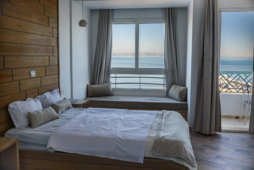 a bedroom with a bed and a view of the ocean at Palm Hotel Le Kram in Le Kram